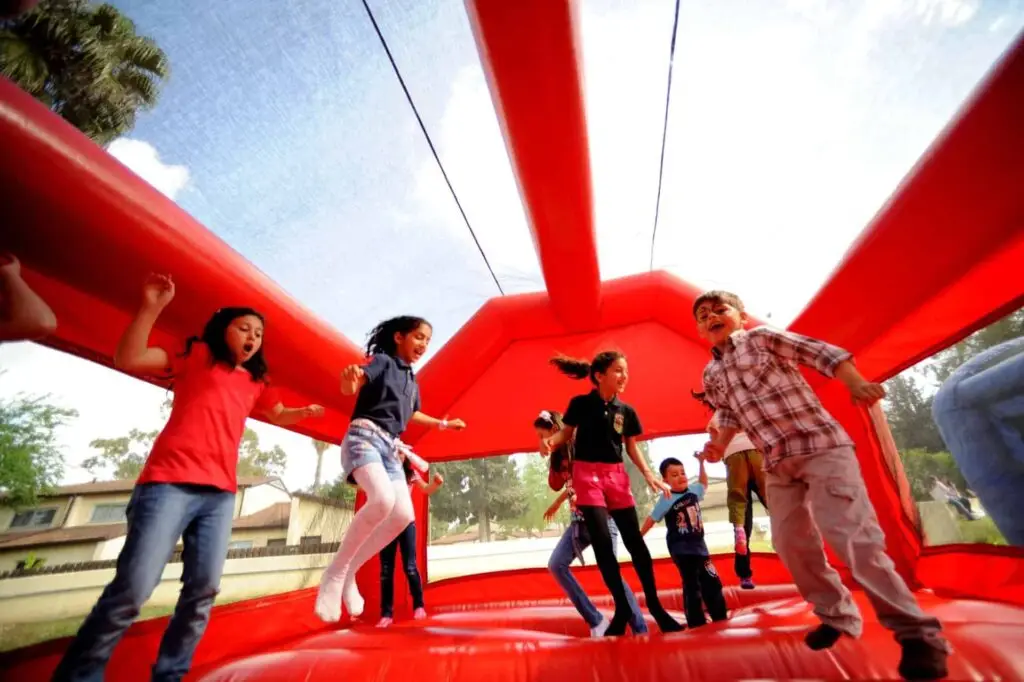 Children enjoying an bounce house obstacle activity at an outdoor event